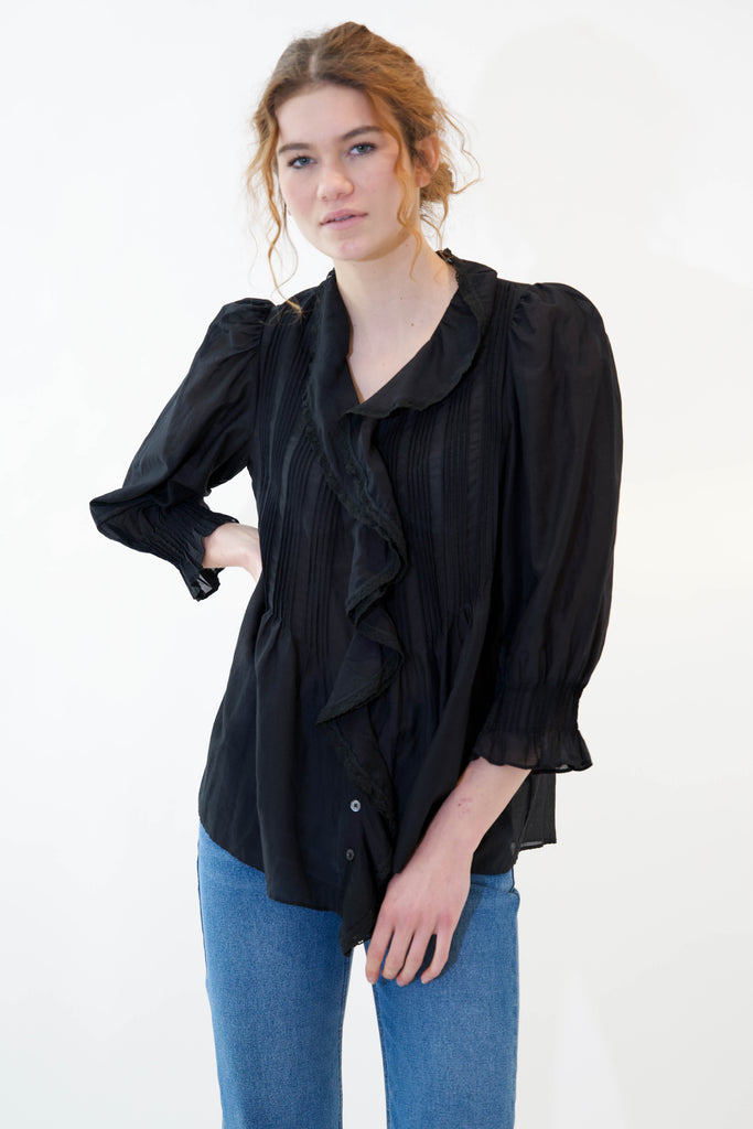 Model with hand on hip wearing amber blouse