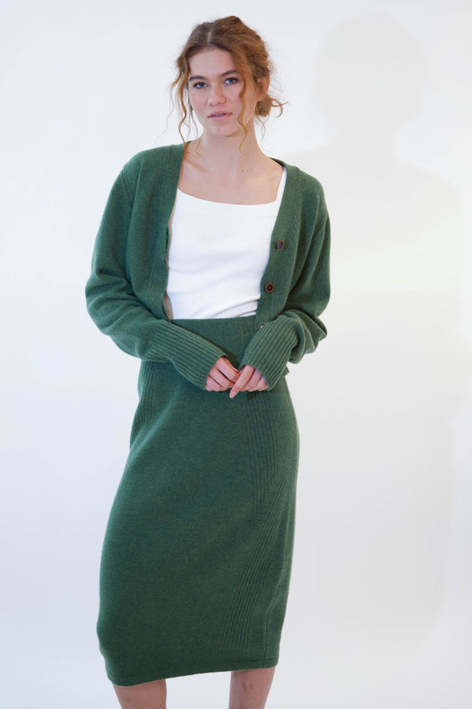 Woman posing while wearing alicia green cardigan on white background