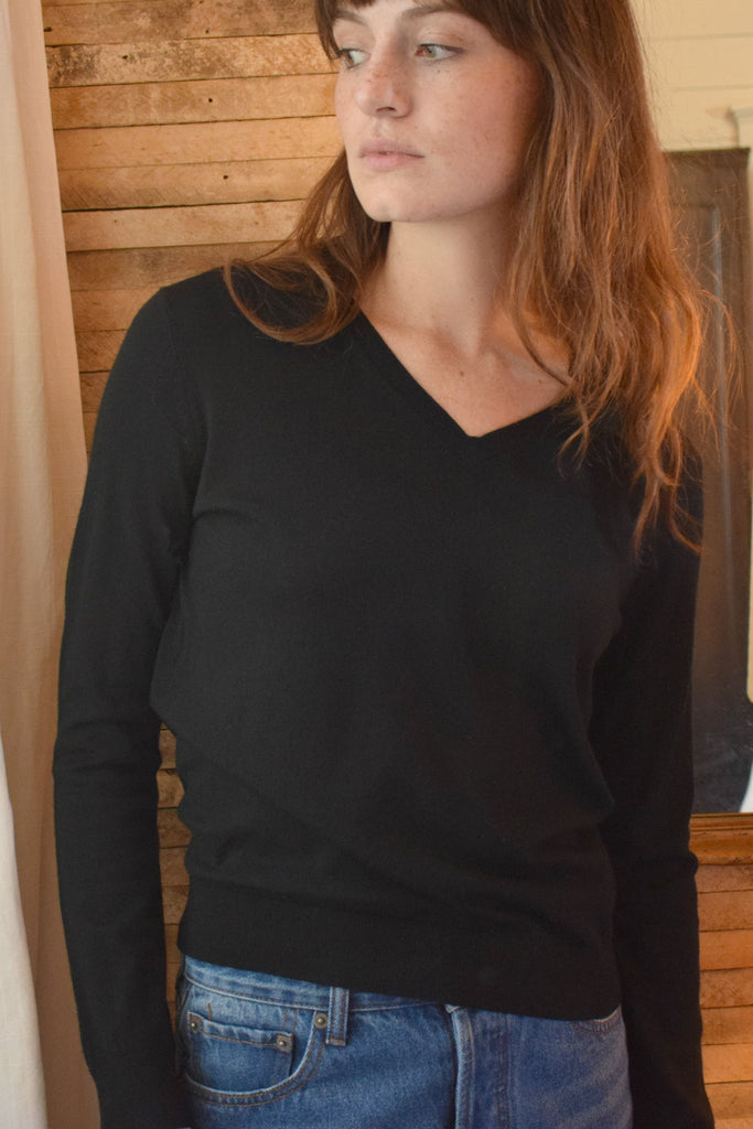 Model posing indoors while wearing andie black pullover