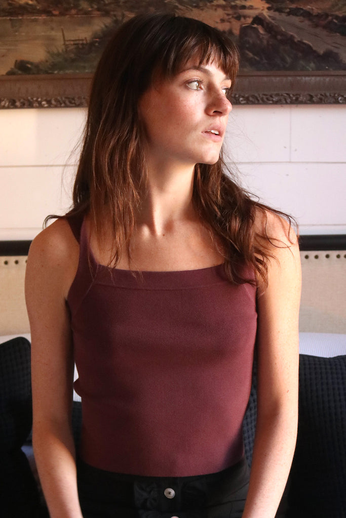 Woman looking to the side while wearing burgundy ribbed knit tank top