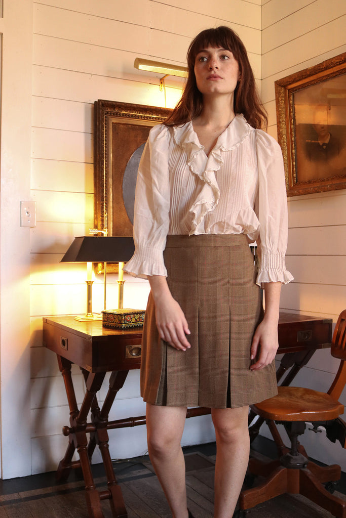 Woman indoors wearing amber blouse and brown skirt