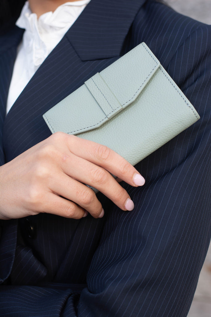 close up of woman holding green athena envelope wallet
